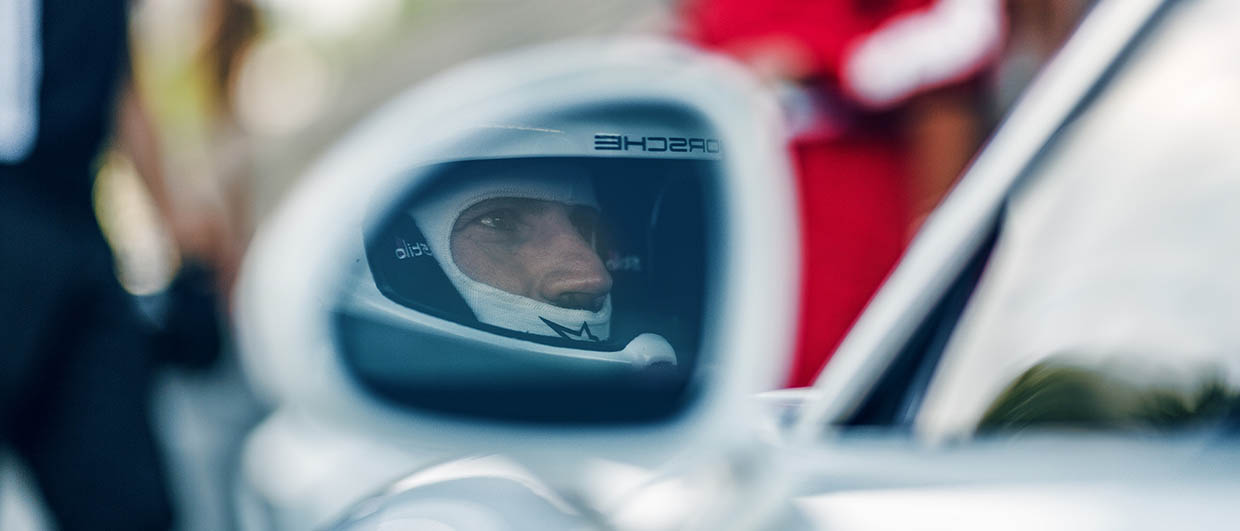 Image in door mirror of driver in race helmet