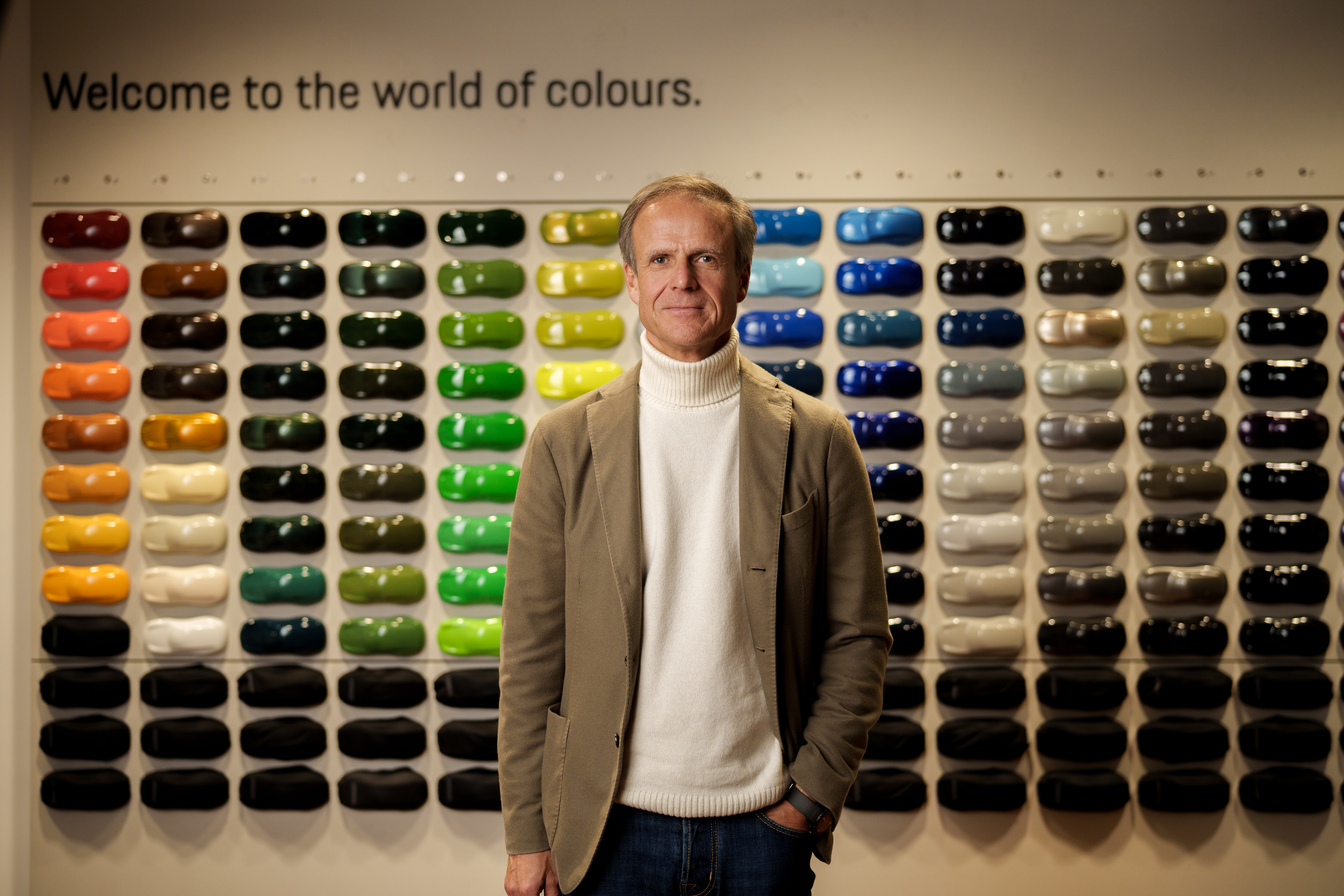 Man in rollneck sweater in front of car colour samples