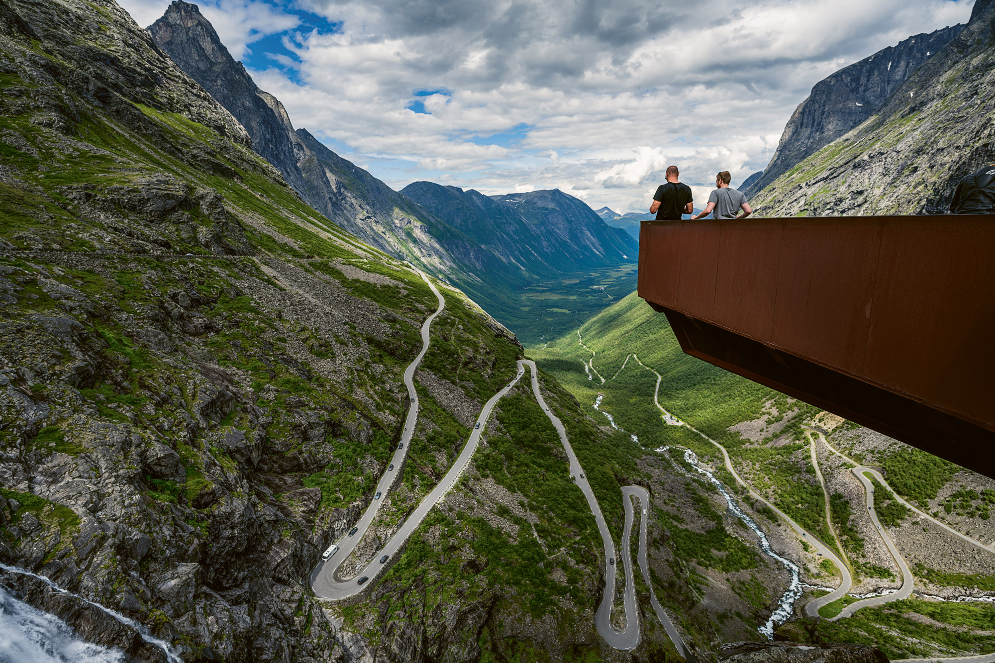 Two men on platform enjoy view of valley roads below