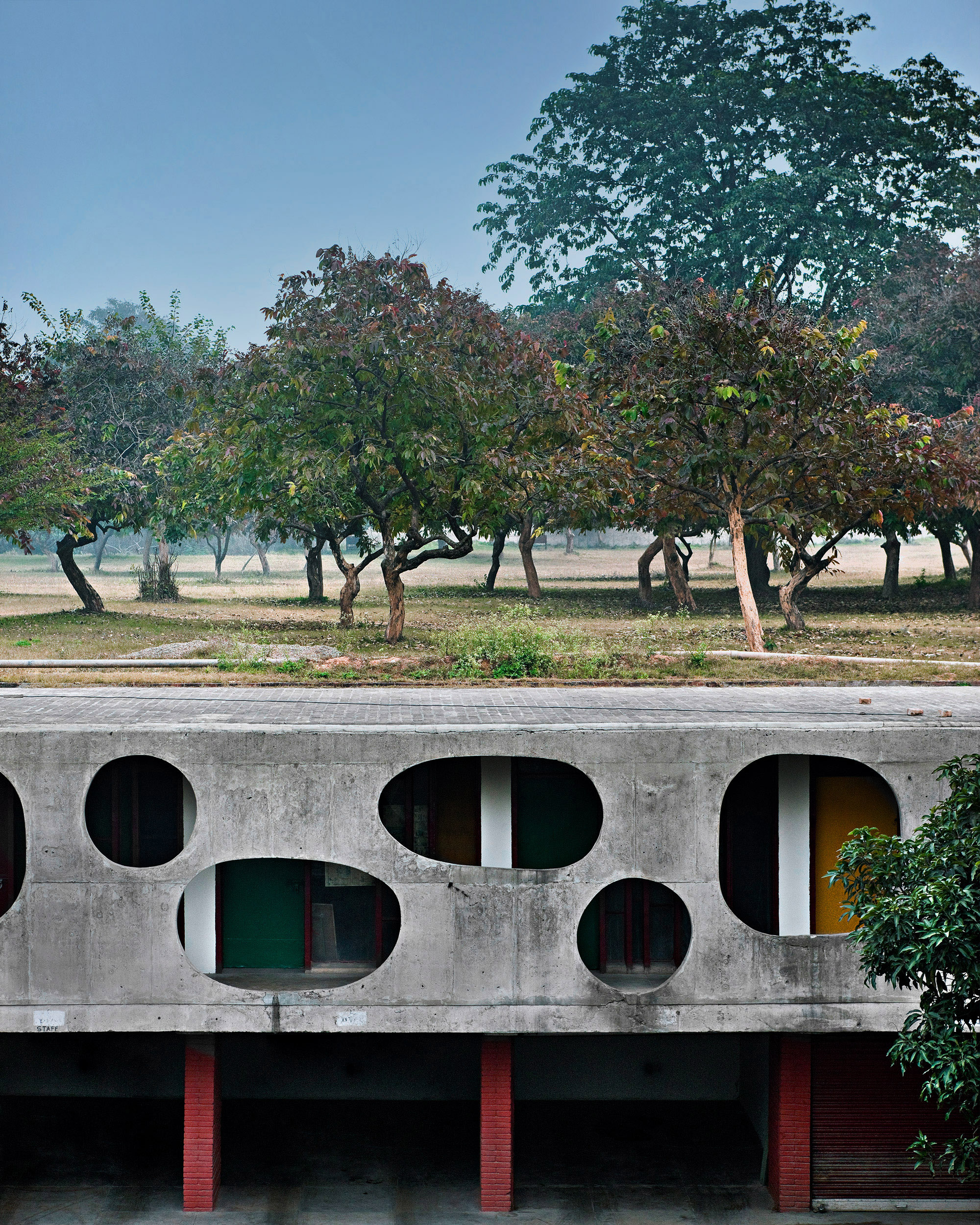 Modernist facade made from exposed concrete with woodland behind 
