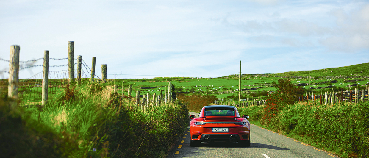 Red Porsche 911 Turbo drives through Irish countryside