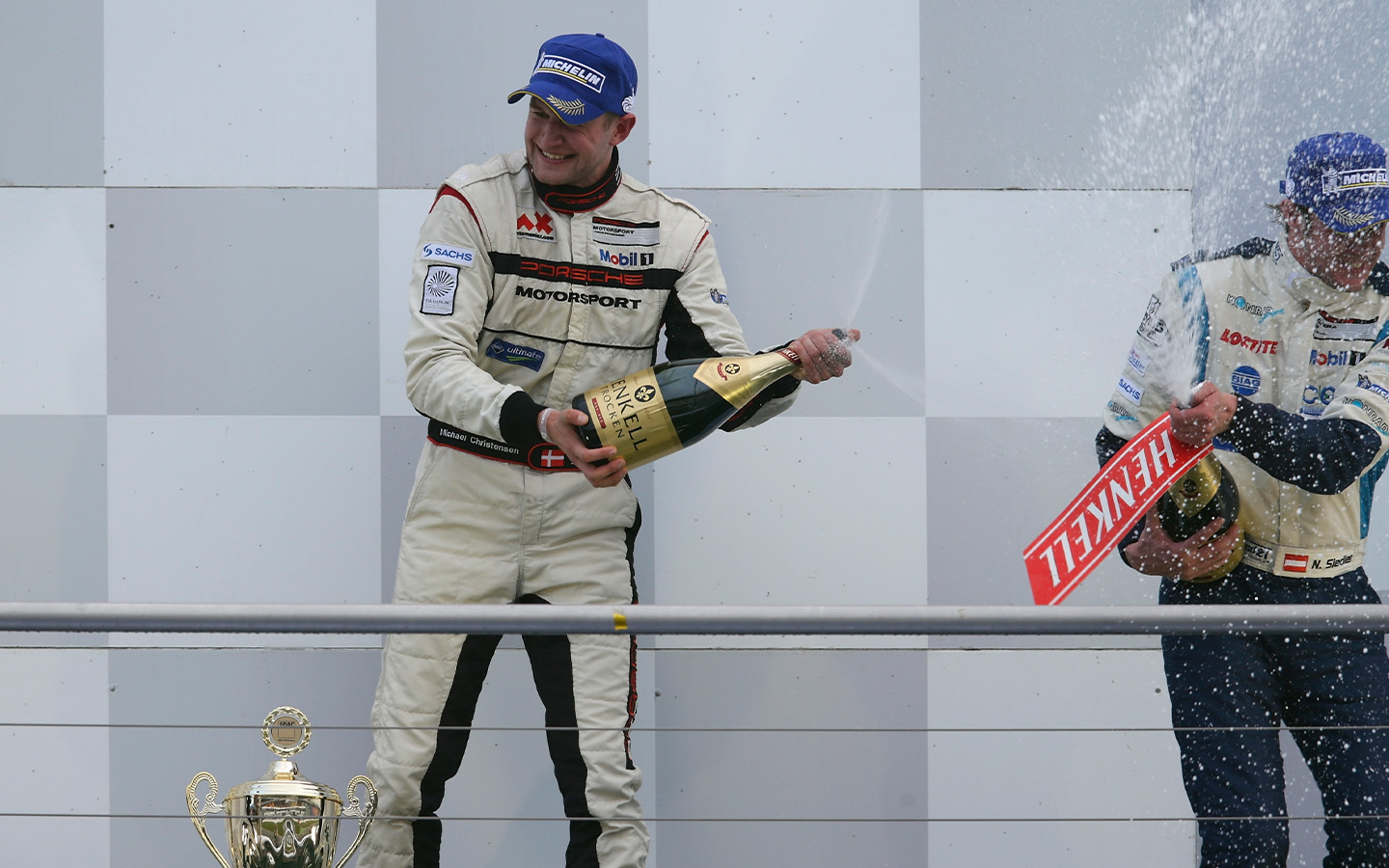 Racing driver Michael Christensen sprays champagne on podium after race