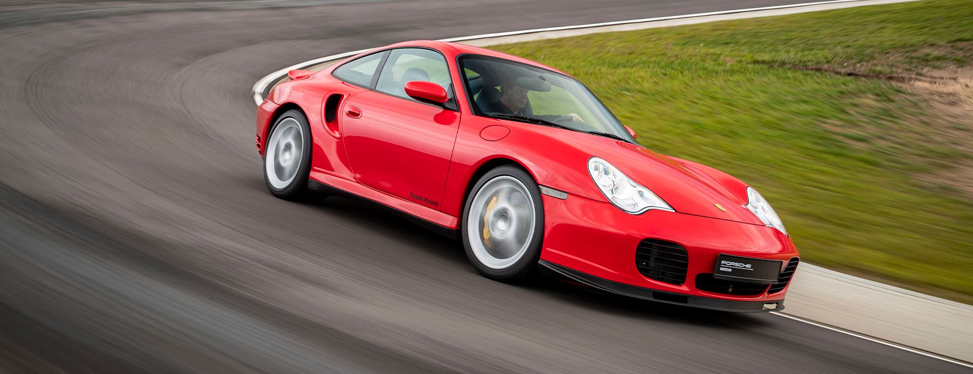 Red Porsche 911 Turbo speeding around bend of racetrack