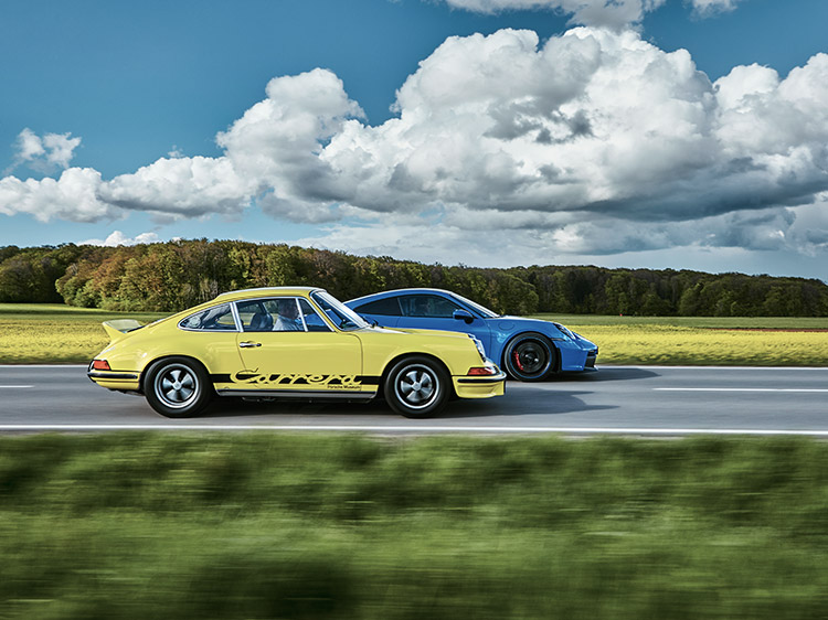 Two Porsche sportscars overtaking in front of yellow fields