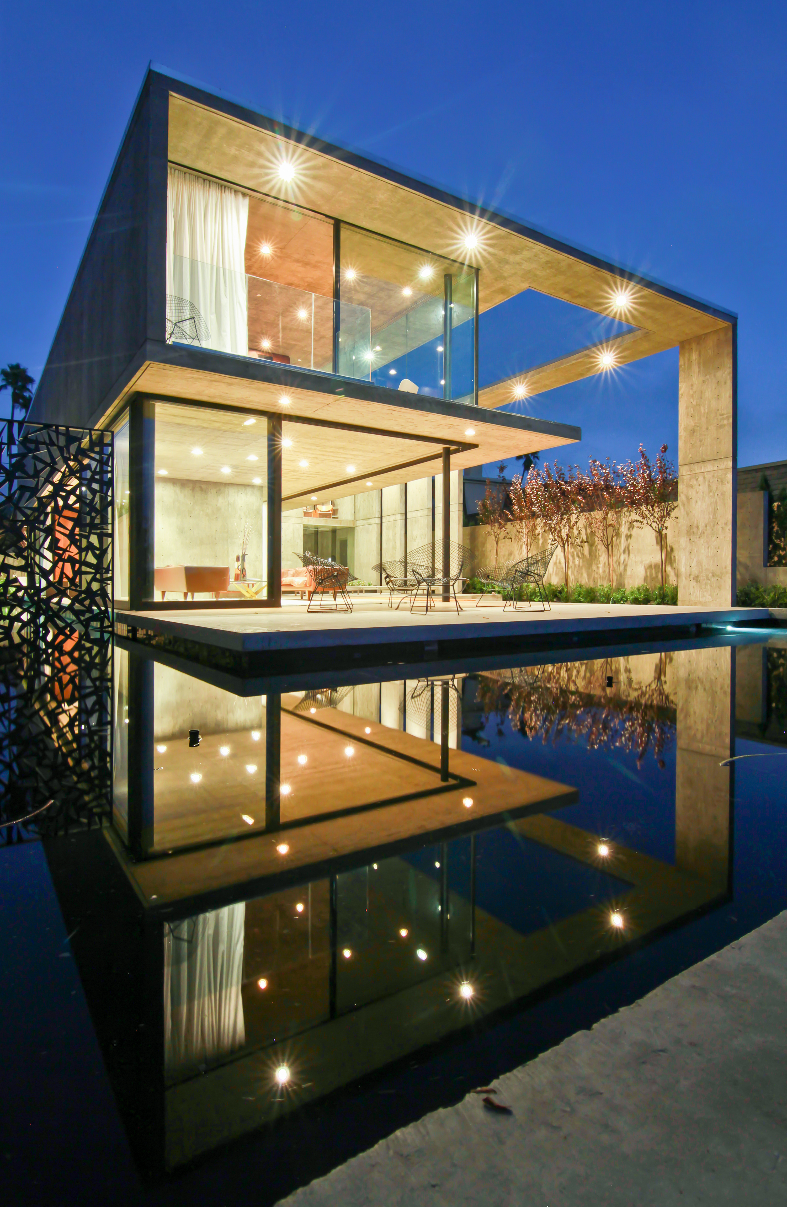 Designer house at night, lit up, surrounded by water