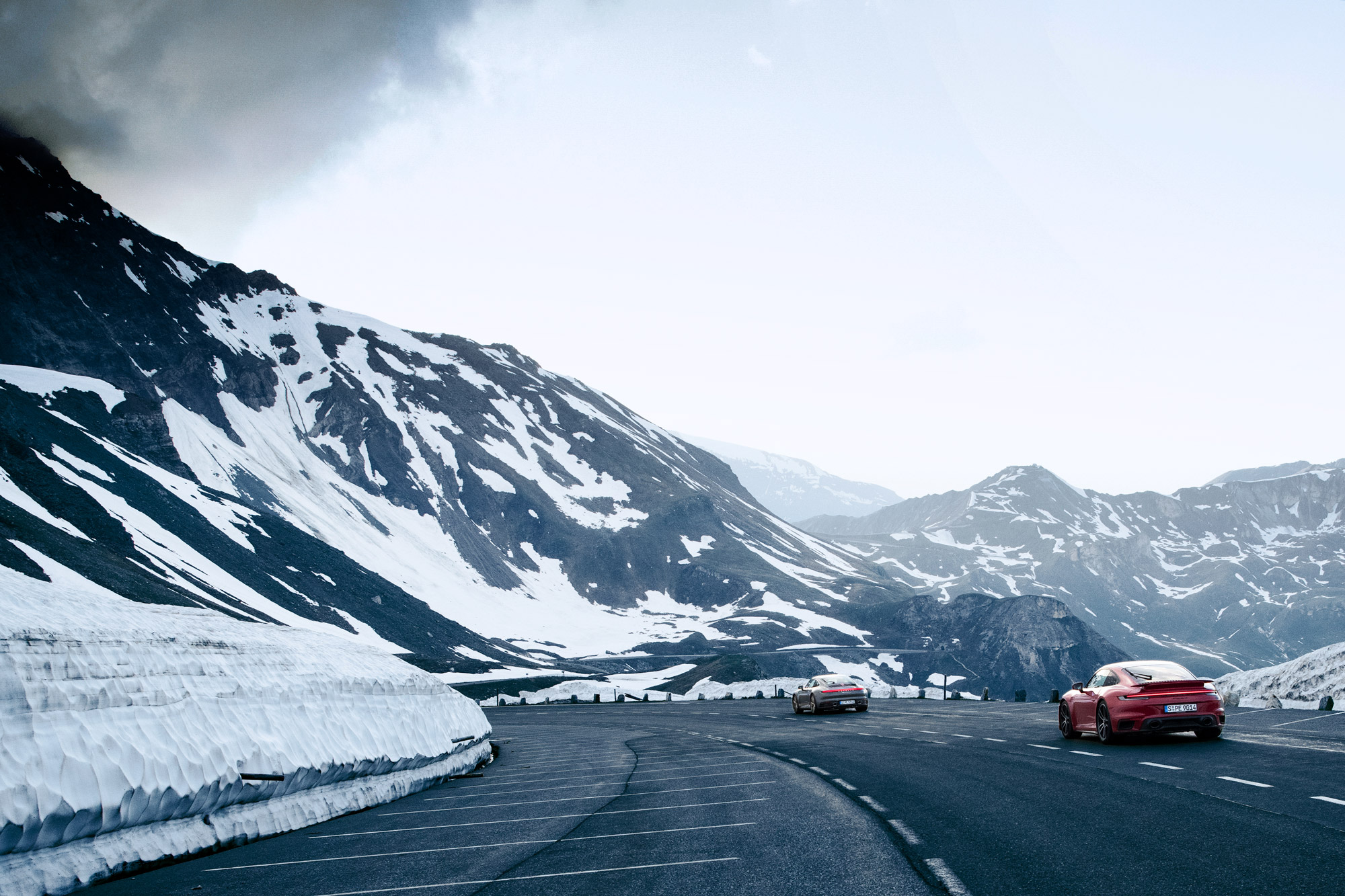 2 Porsche 911 on a mountain road, overlooking a valley