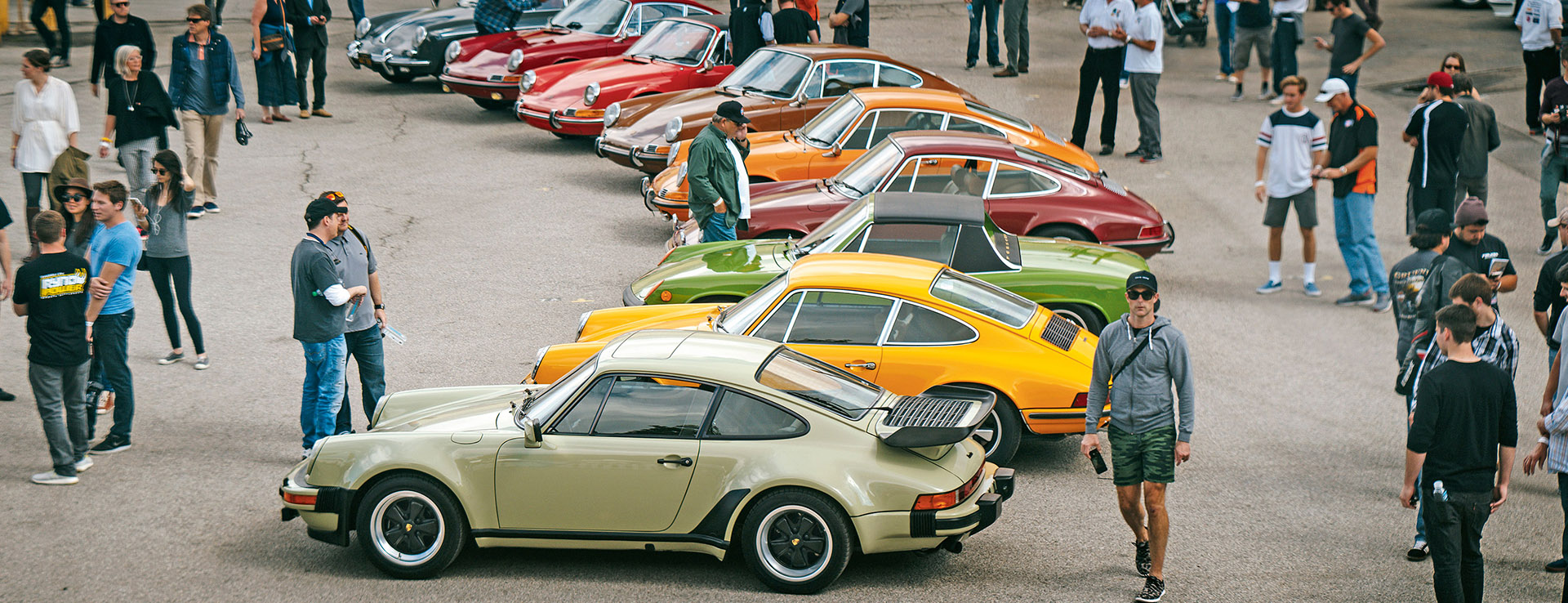 Large line-up of classic Porsche sportscars at show, urban location