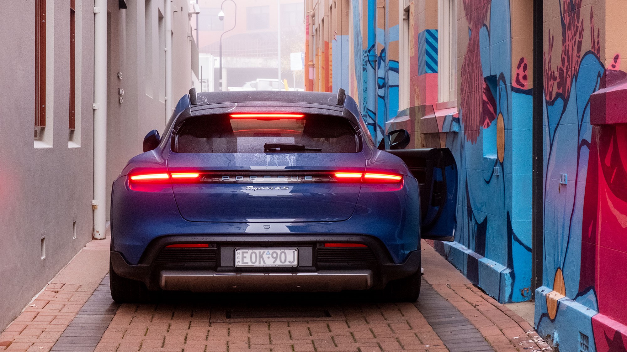 Blue Porsche Taycan 4S Cross Turismo next to graffitied wall