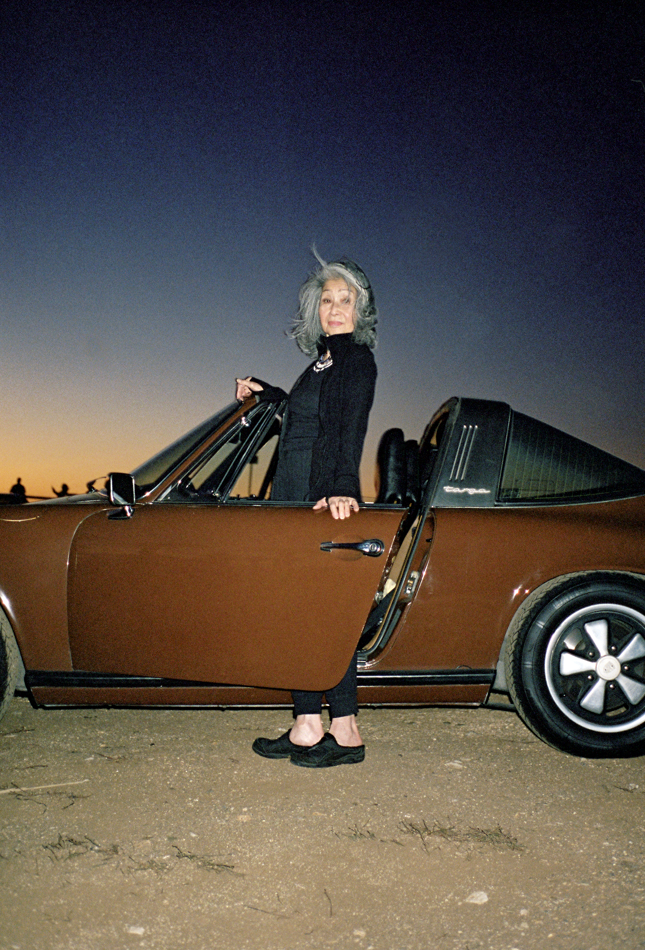 Elegant lady with classic brown Porsche 911 at twilight