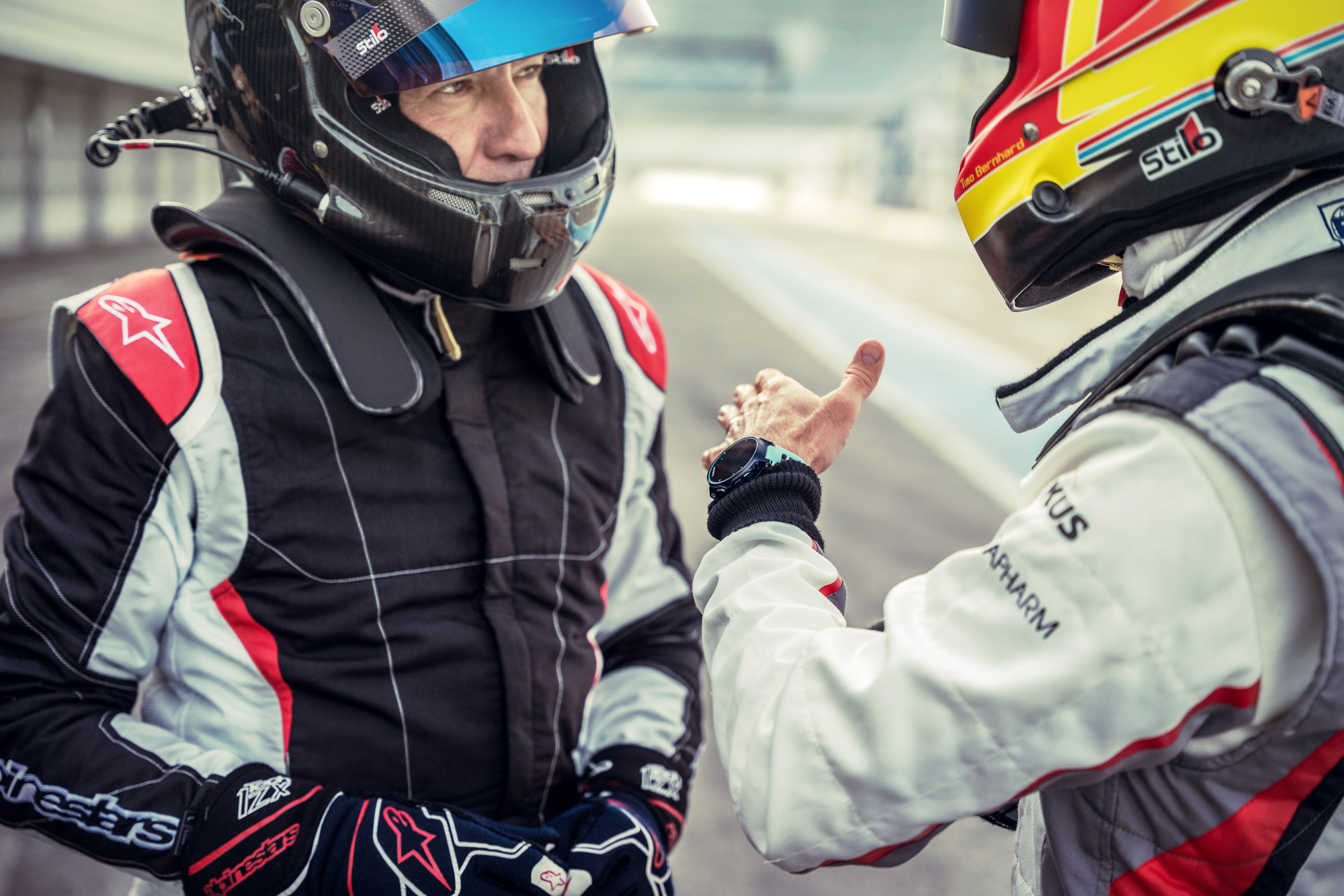 Two race drivers in helmets chatting