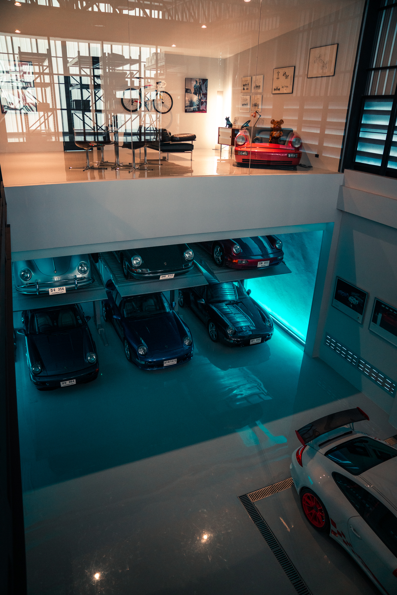 Six Porsche cars lined up on lifts in a garage