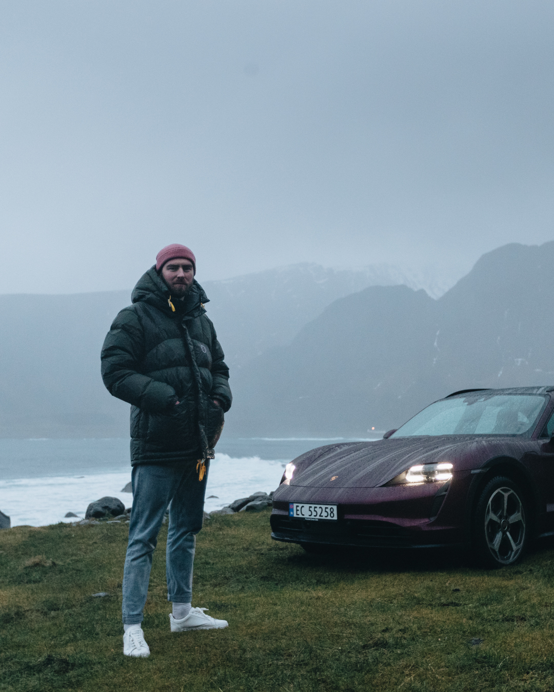 Man stands in front of Taycan Cross Turismo and misty mountain scene