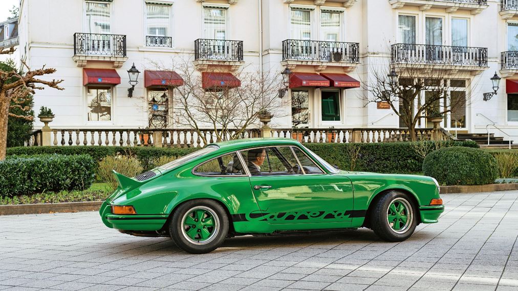 Green Porsche 911 Carrera RS 2.7 in front of apartments