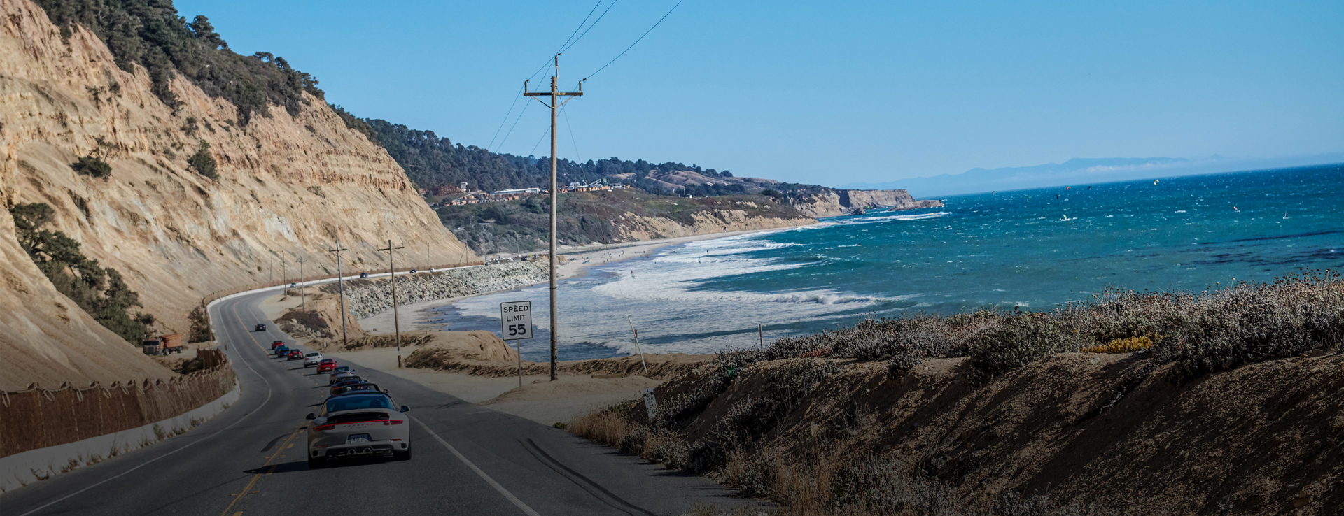 A coastal road between sandstone cliffs and surf-ready ocean