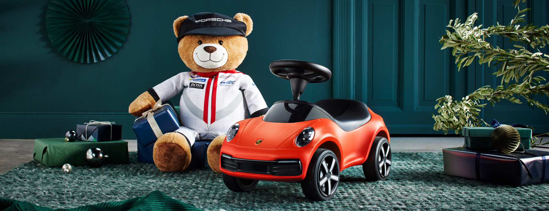 Red baby Porsche 911 next to teddy dressed as a racing driver