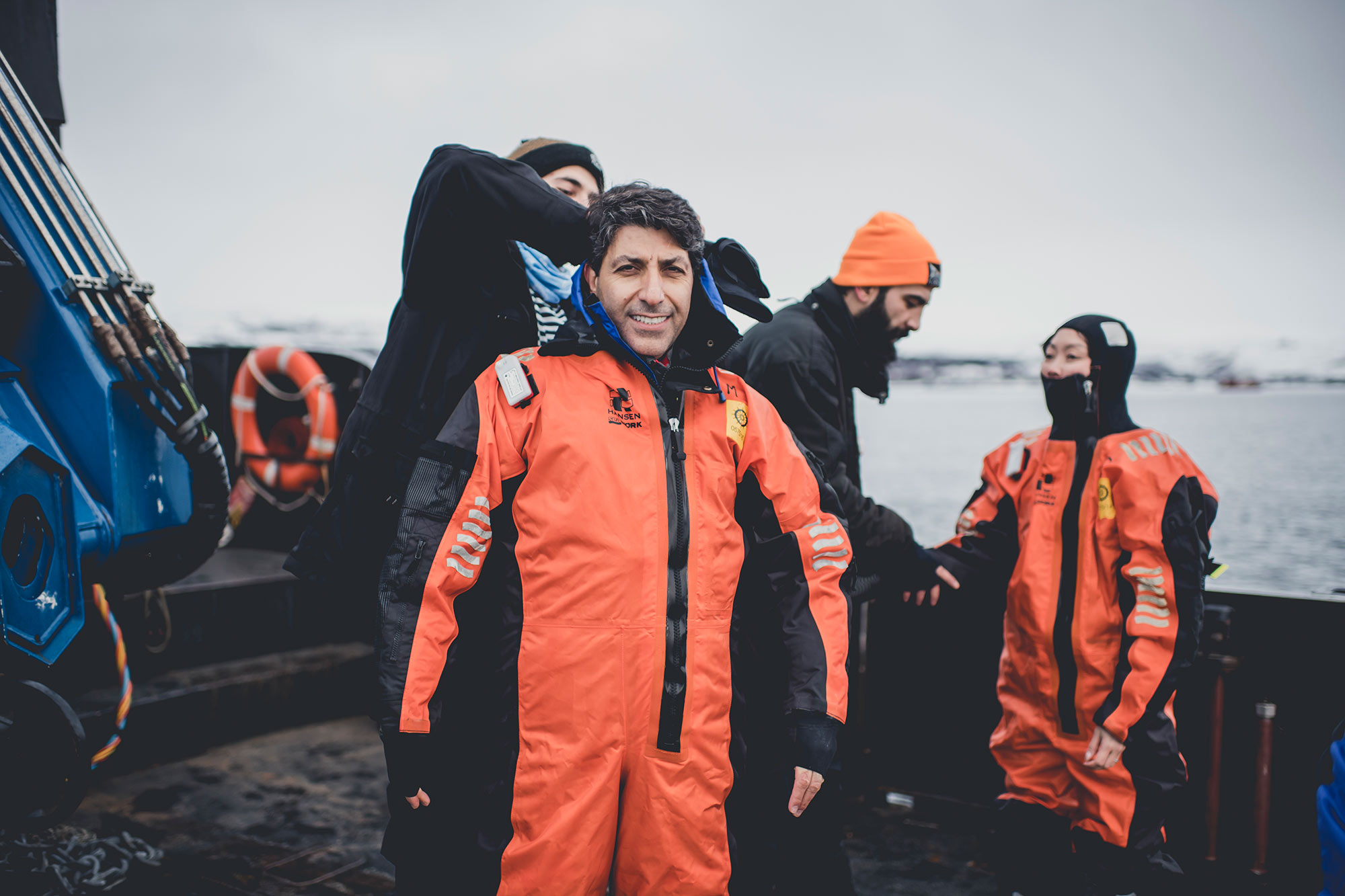 Two ice swimmers being zipped into protective orange suits