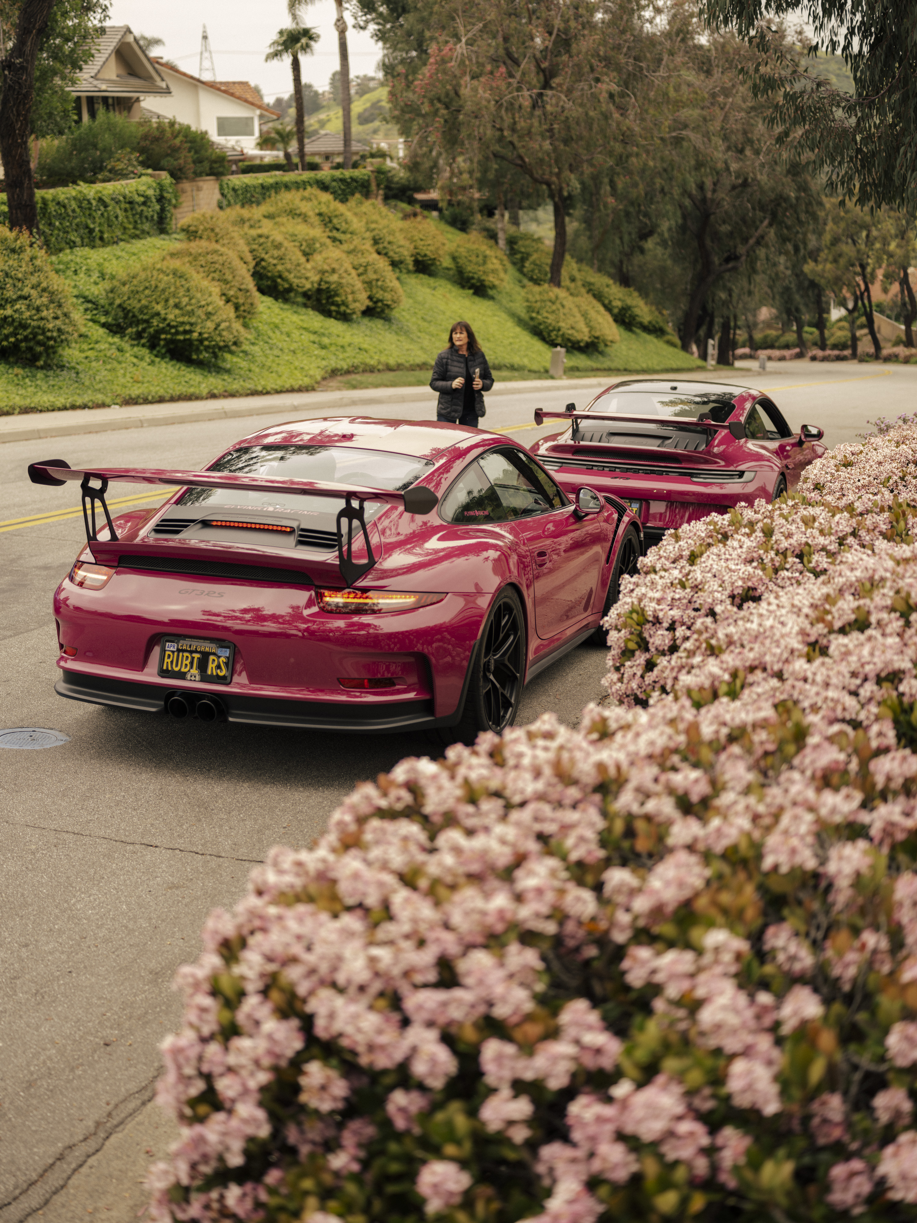 Woman standing beside two Porsche 911 GT3 RS sportscars