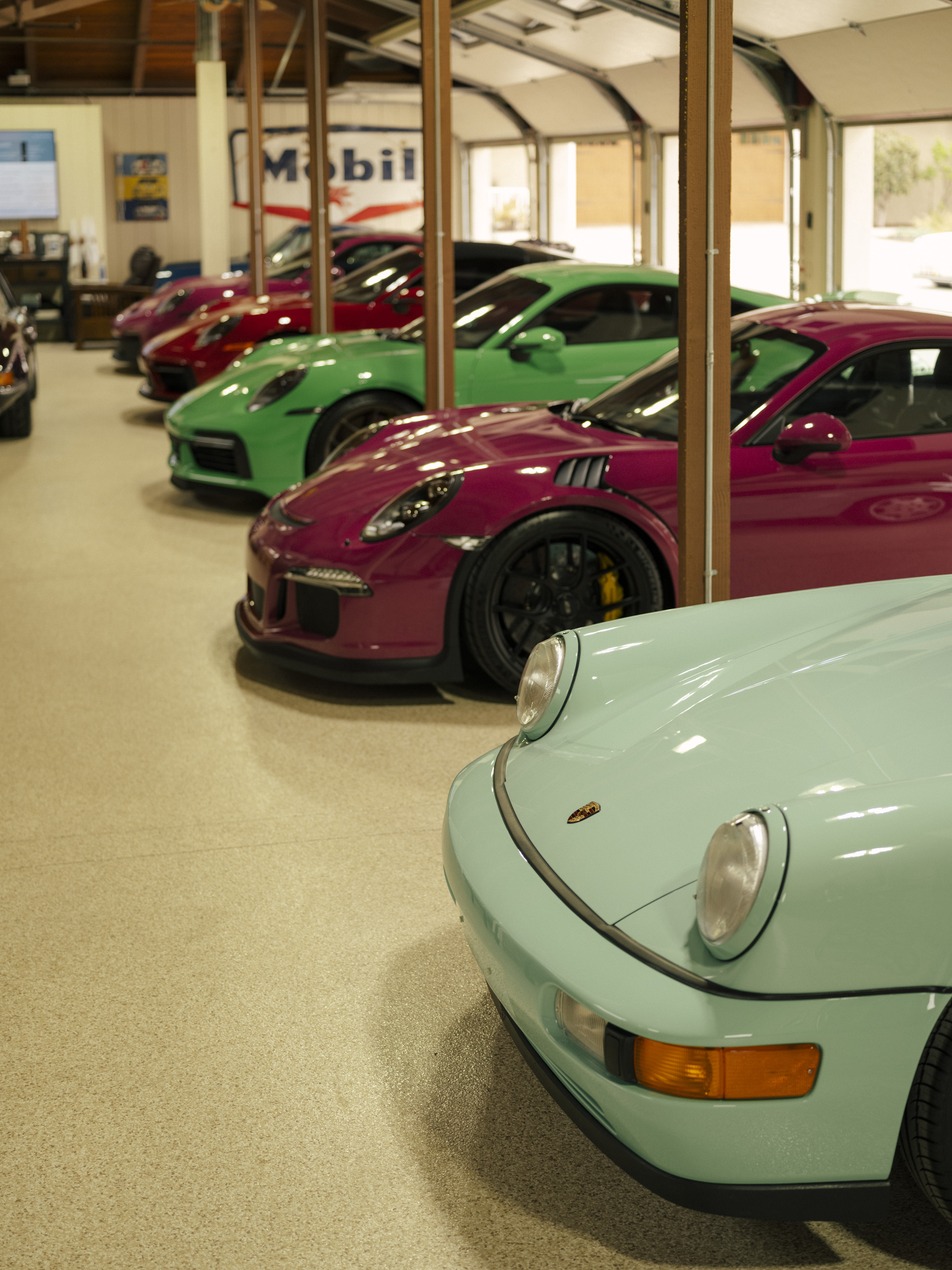 Line-up of colourful Porsche 911 cars in a garage