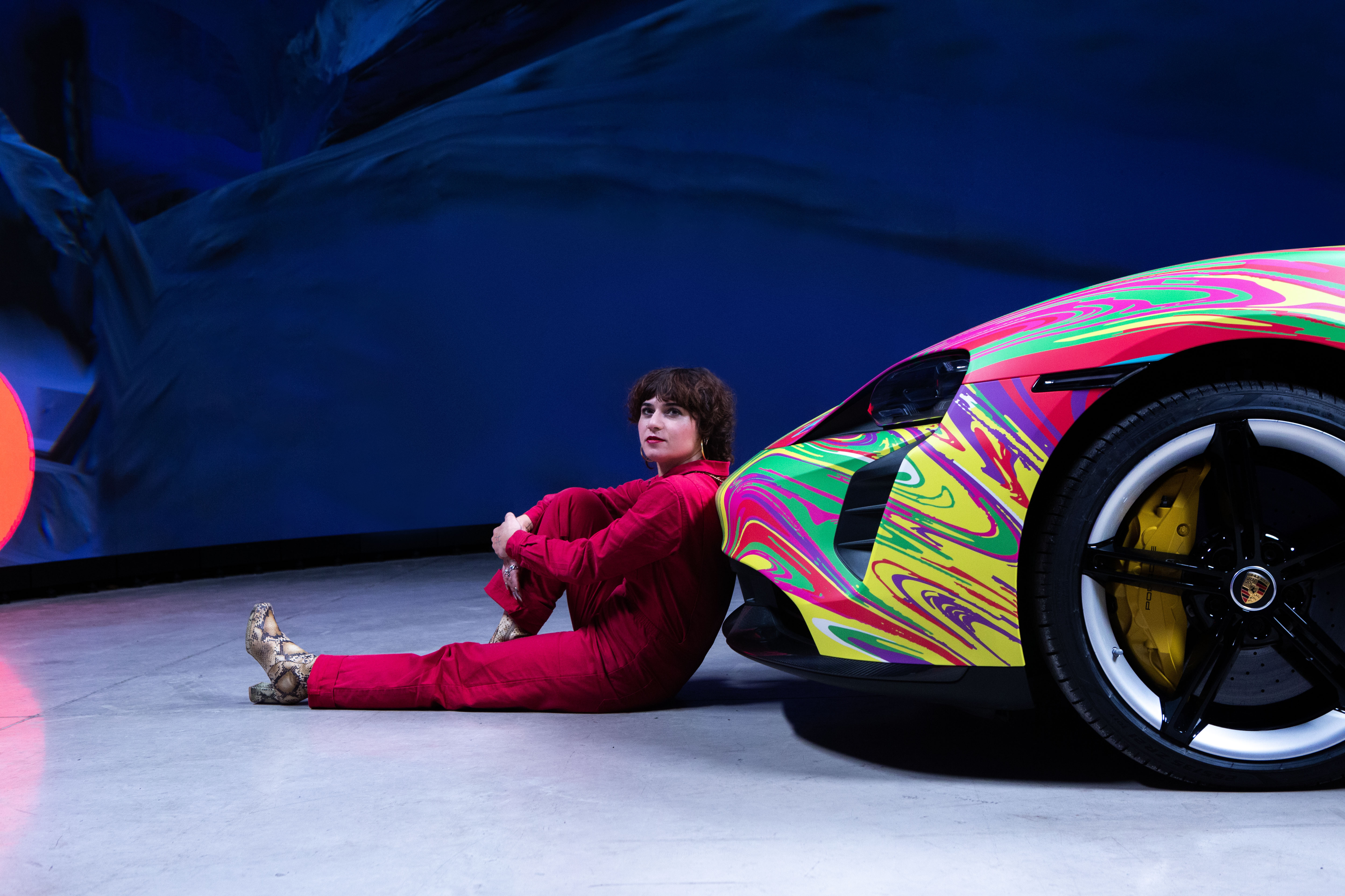 Woman leaning against bumper of Porsche Taycan art car
