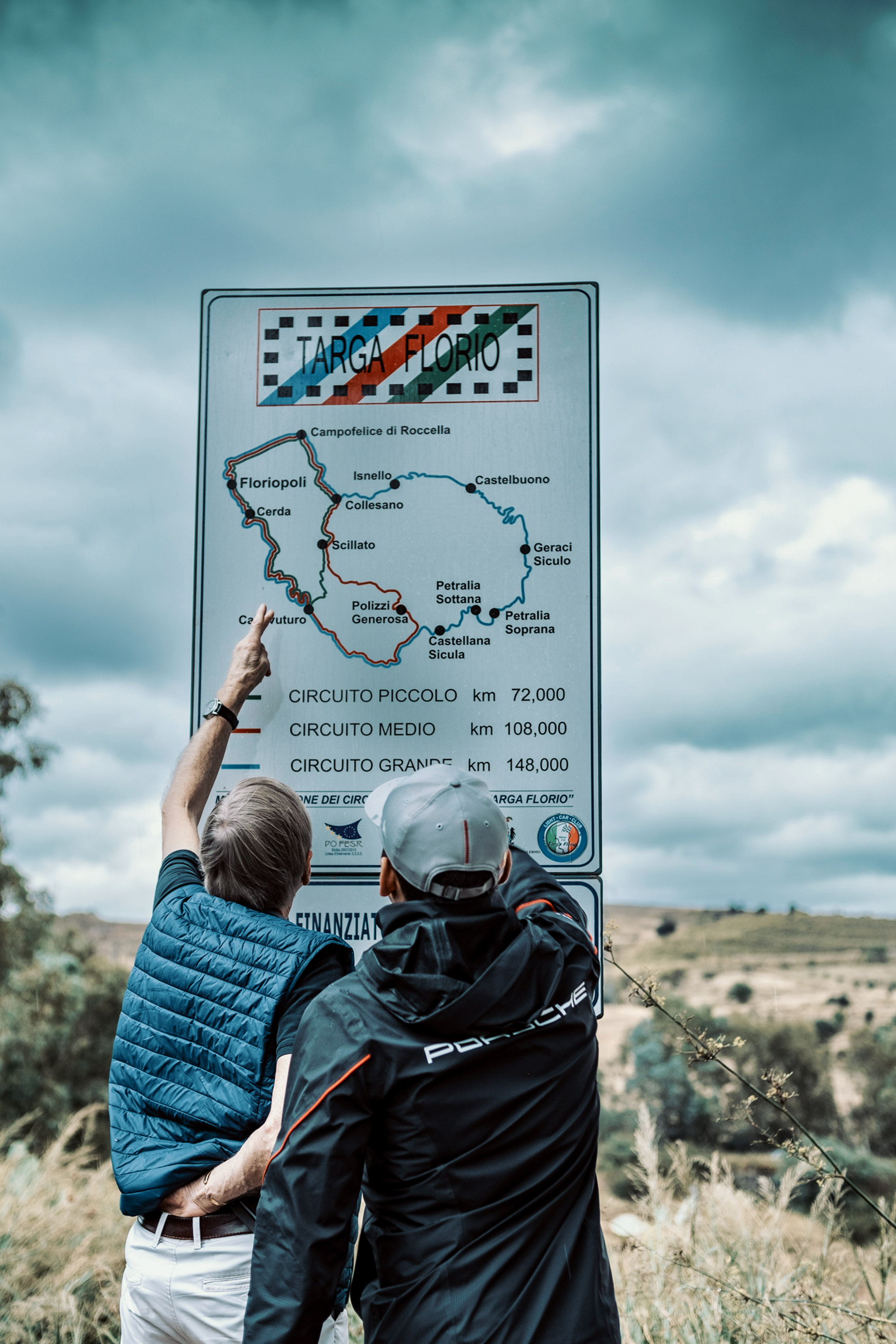 Two men study street sign showing map of Targa Florio