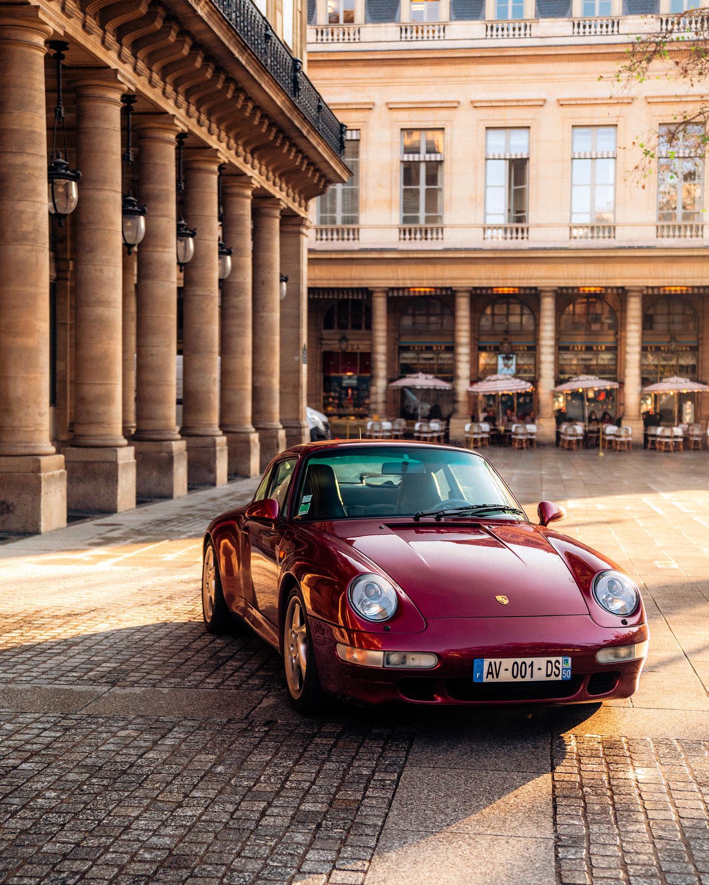 Arena red Porsche 911 parked in sunlit Parisian square