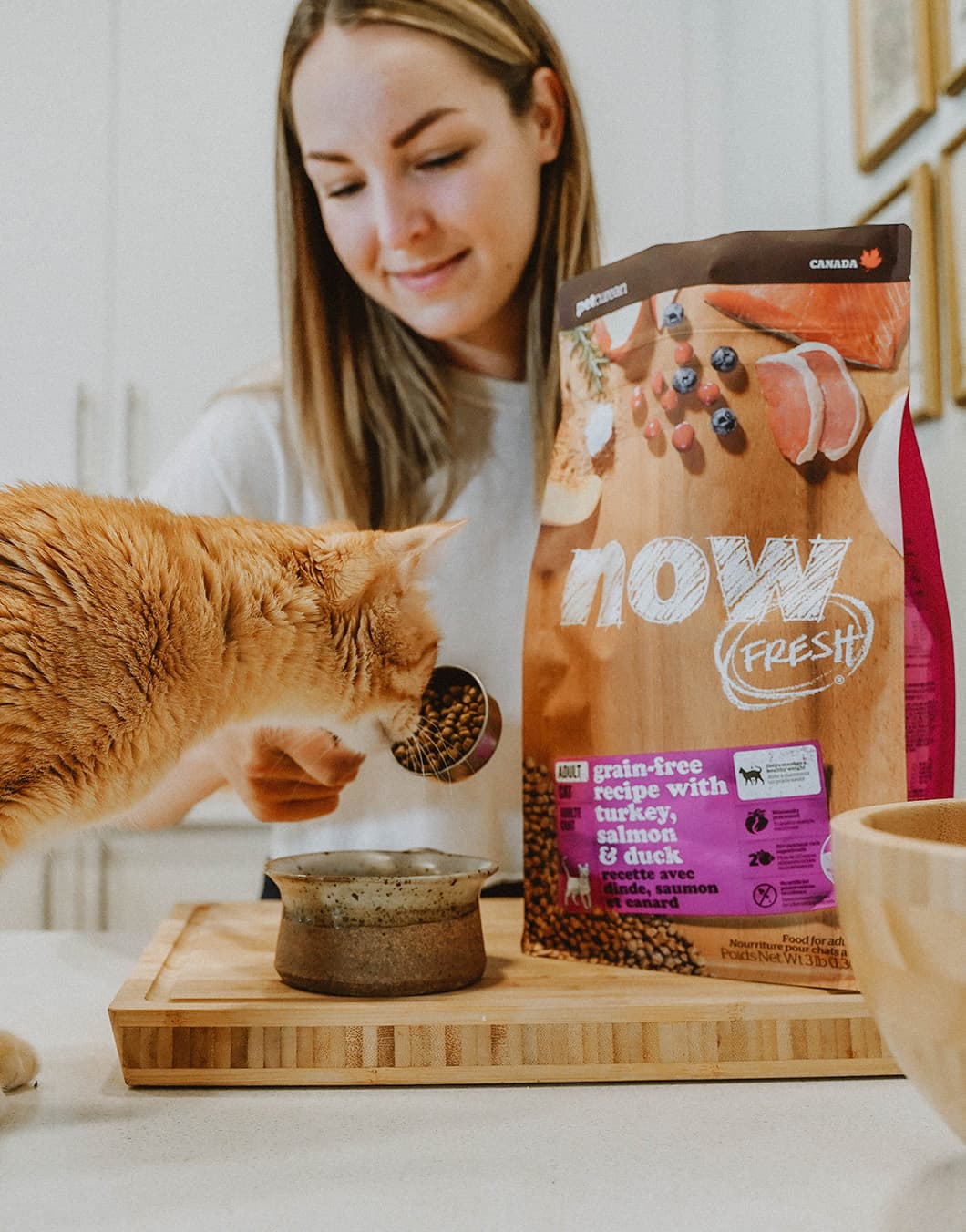 Woman scooping NOW FRESH kibble into bowl for cat