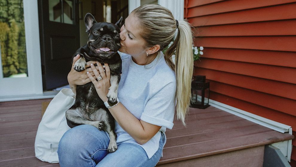 Woman on porch kissing French Bulldog
