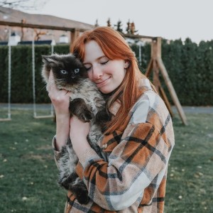 Red haired girl cuddling cat