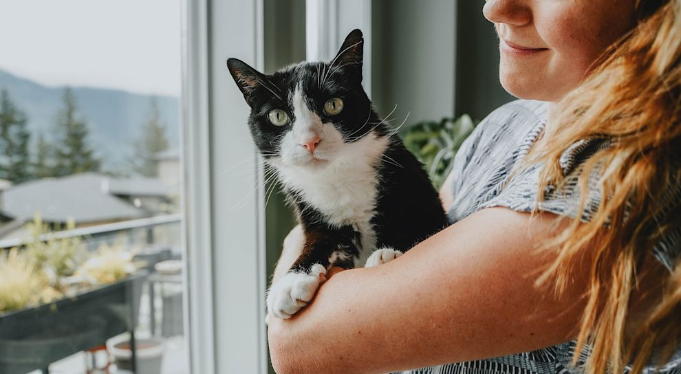 Woman holding black and white cat
