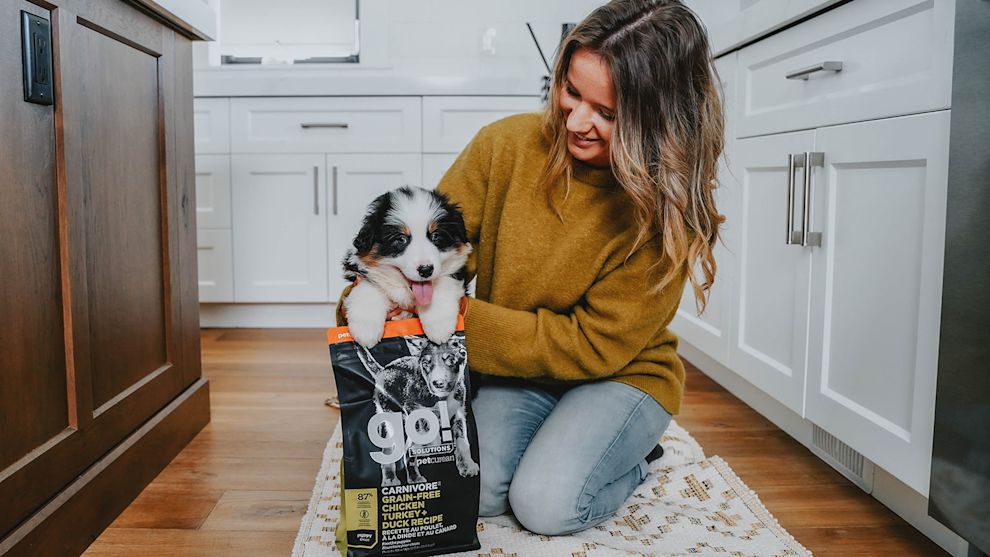 Woman in kitchen with puppy in bag of Go! puppy food