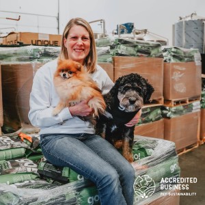 Woman sitting on pallet of dog food with two dogs