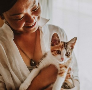 Woman in white blouse holding calico kitten