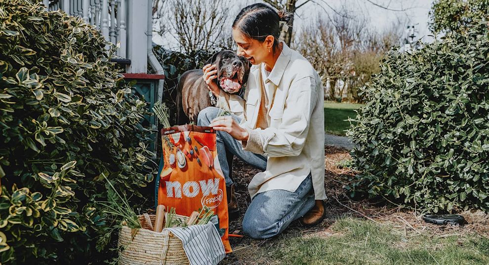 Pet parent and dog outdoors in garden with bag of Now Fresh 