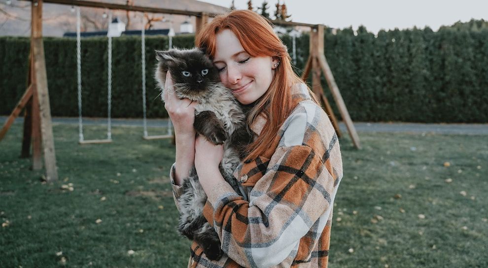 Red haired woman hugging cat outside