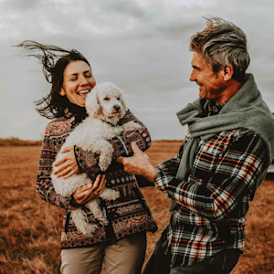 Happy couple holding a white poodle outdoor