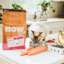 Cat eating Now Fresh kibble on counter with fresh fruits and veggies