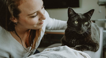 Woman with black cat on sofa