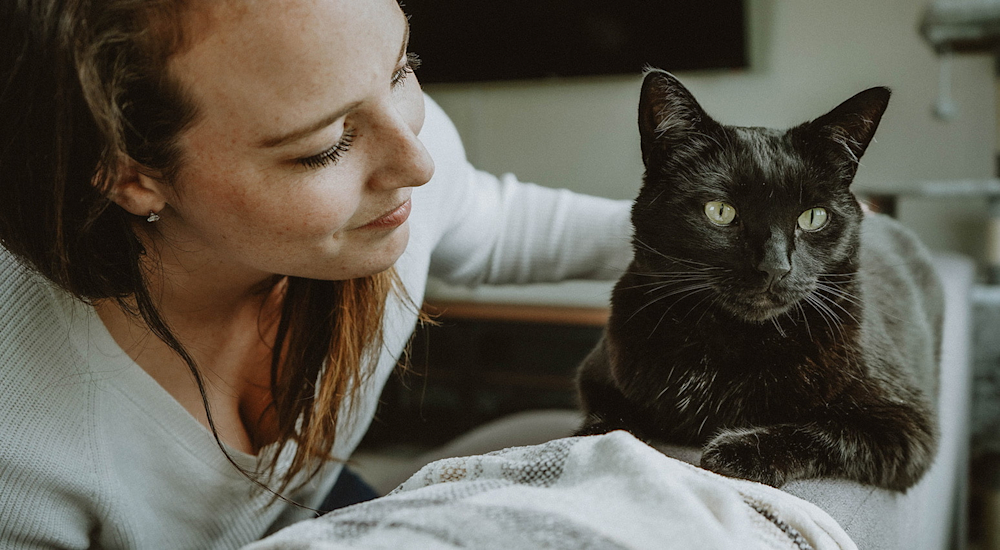 Woman with black cat on sofa