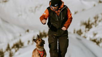 Avalanche dog handler giving dog kibble as reward