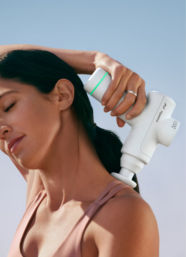 woman using massage gun on her neck