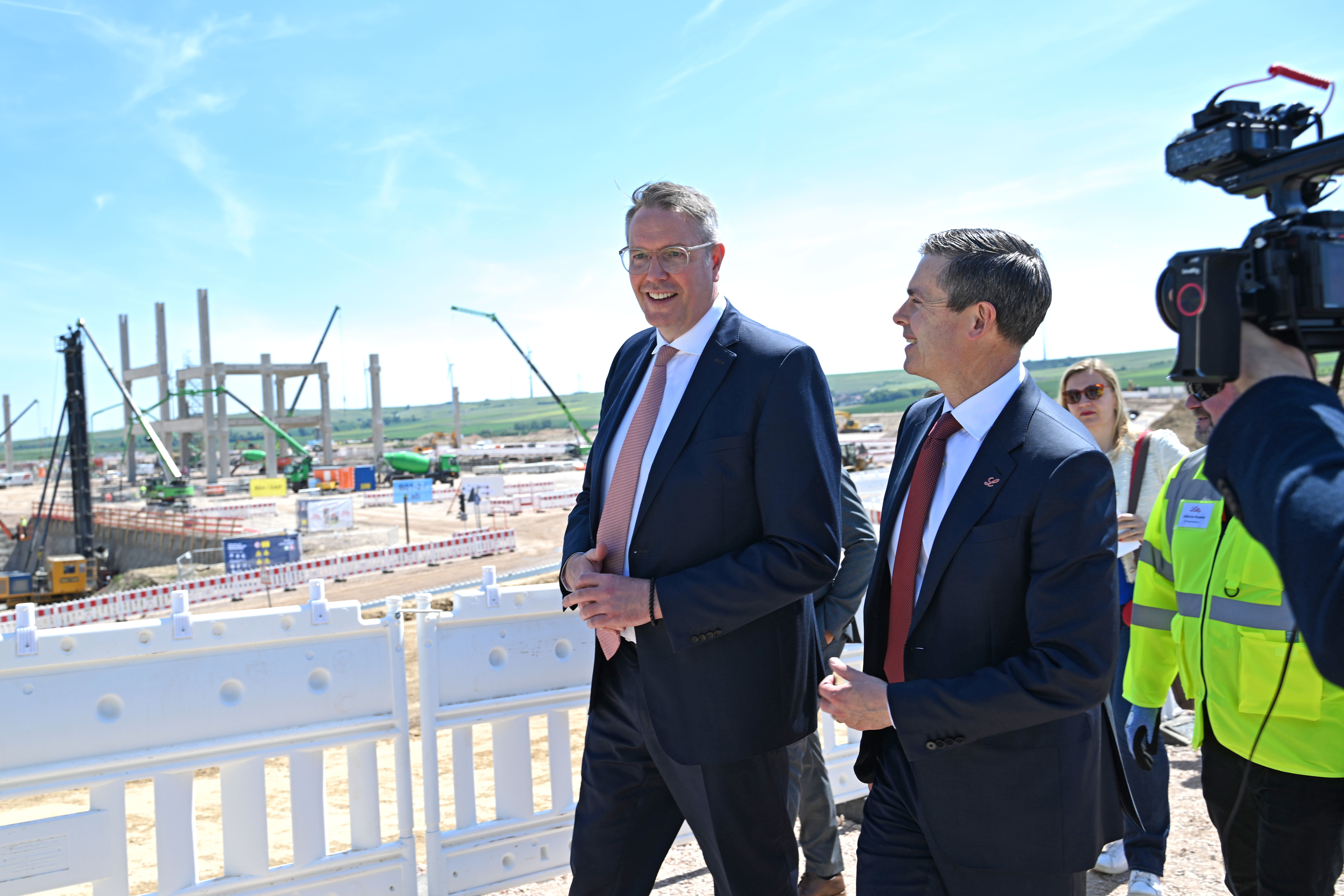 Dave Ricks und Minister Alexander Schweitzer gehen gemeinsam, begleitet von einem Kameramann