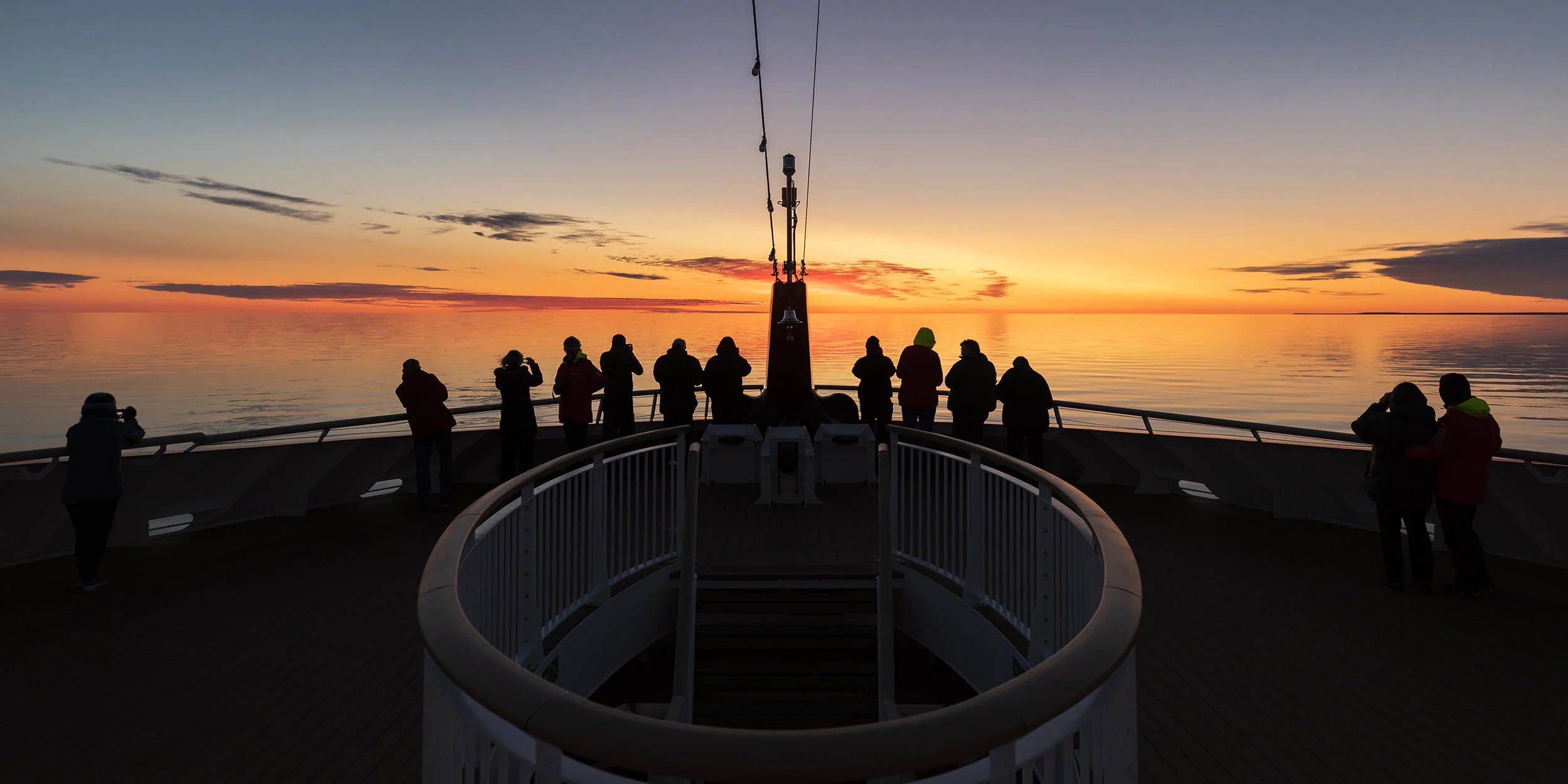Guests enjoying a dramatic sunset from the Observation Deck onboard MS Roald Amundsen in the Northwest Passage, Canada. Credit Karsten Bidstrup. 