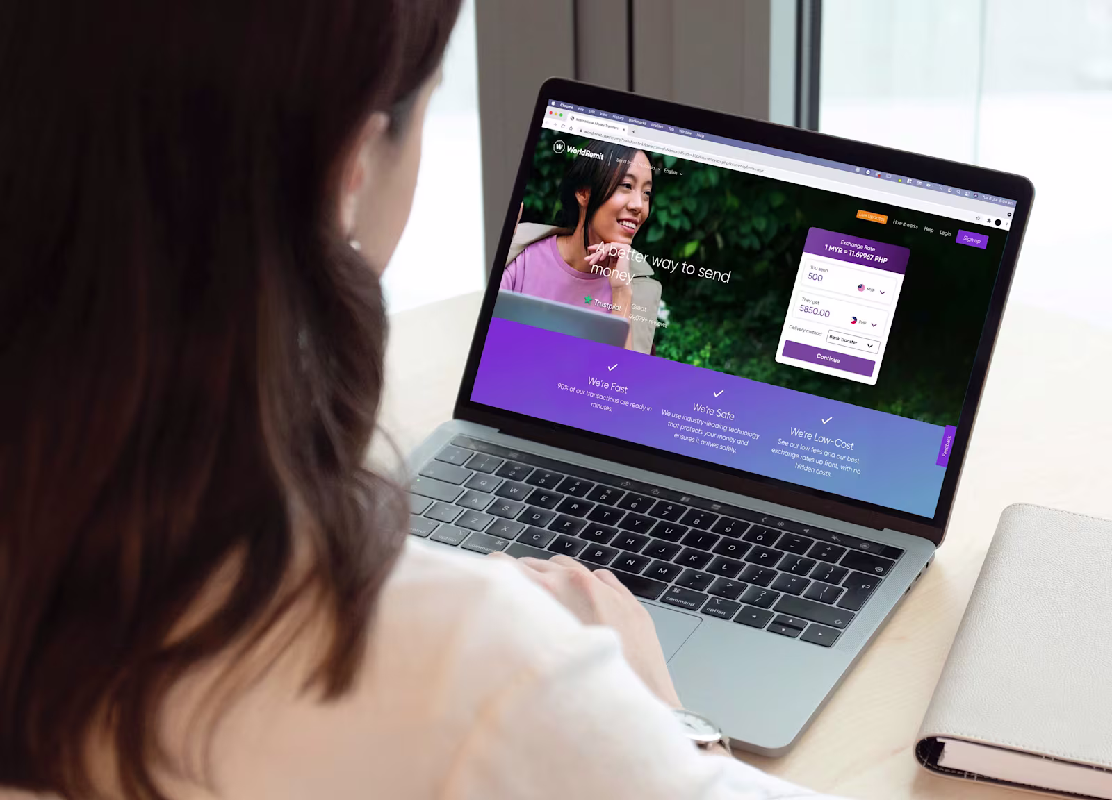 Image of the back of a ladies head, who is looking at the WorldRemit website whilst on a laptop