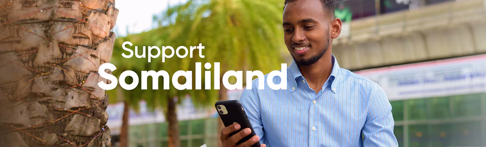 An image showing a Somalian man looking down at his phone and smiling