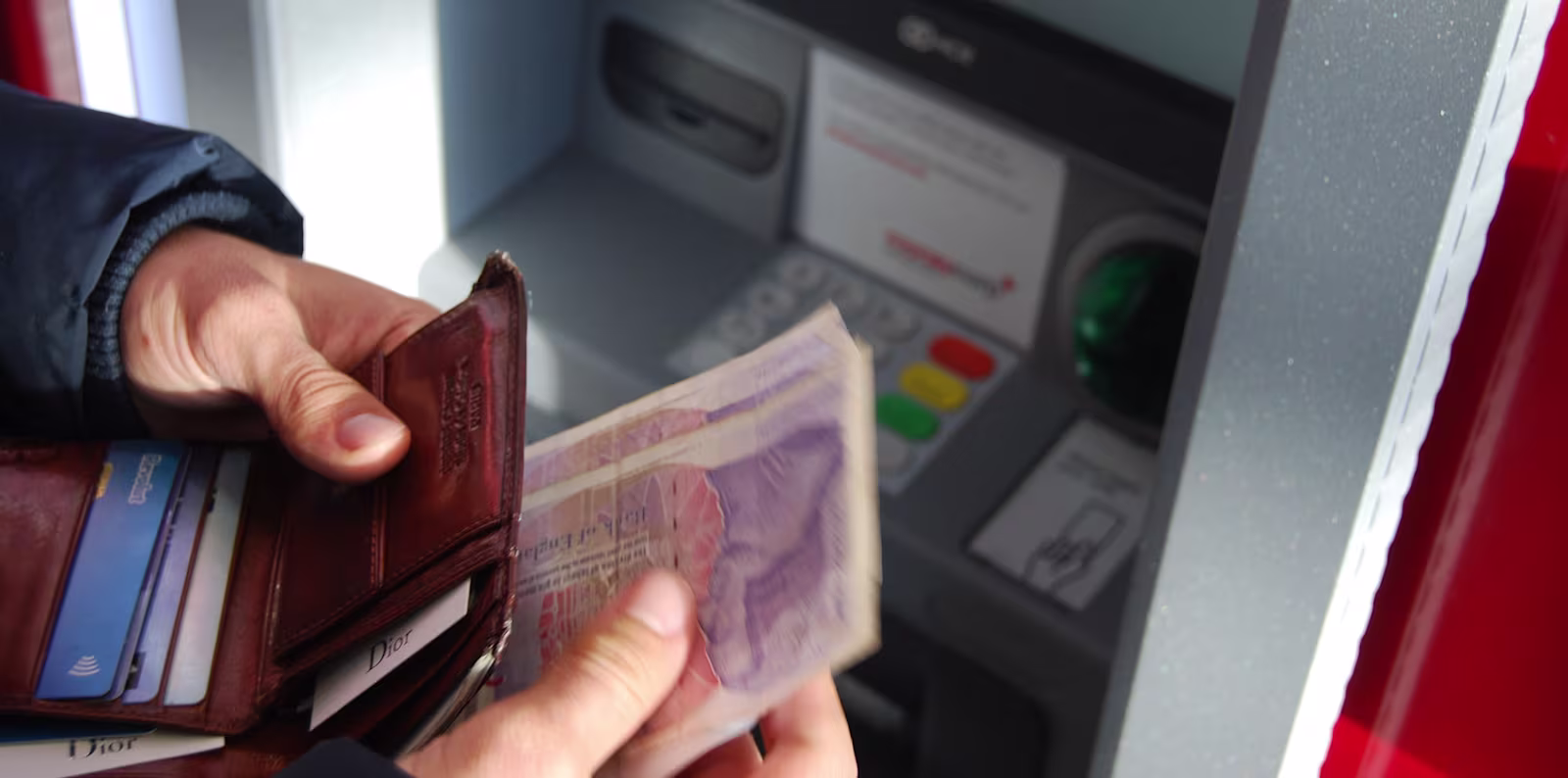 A close image of a man withdrawing cash from an ATM machine
