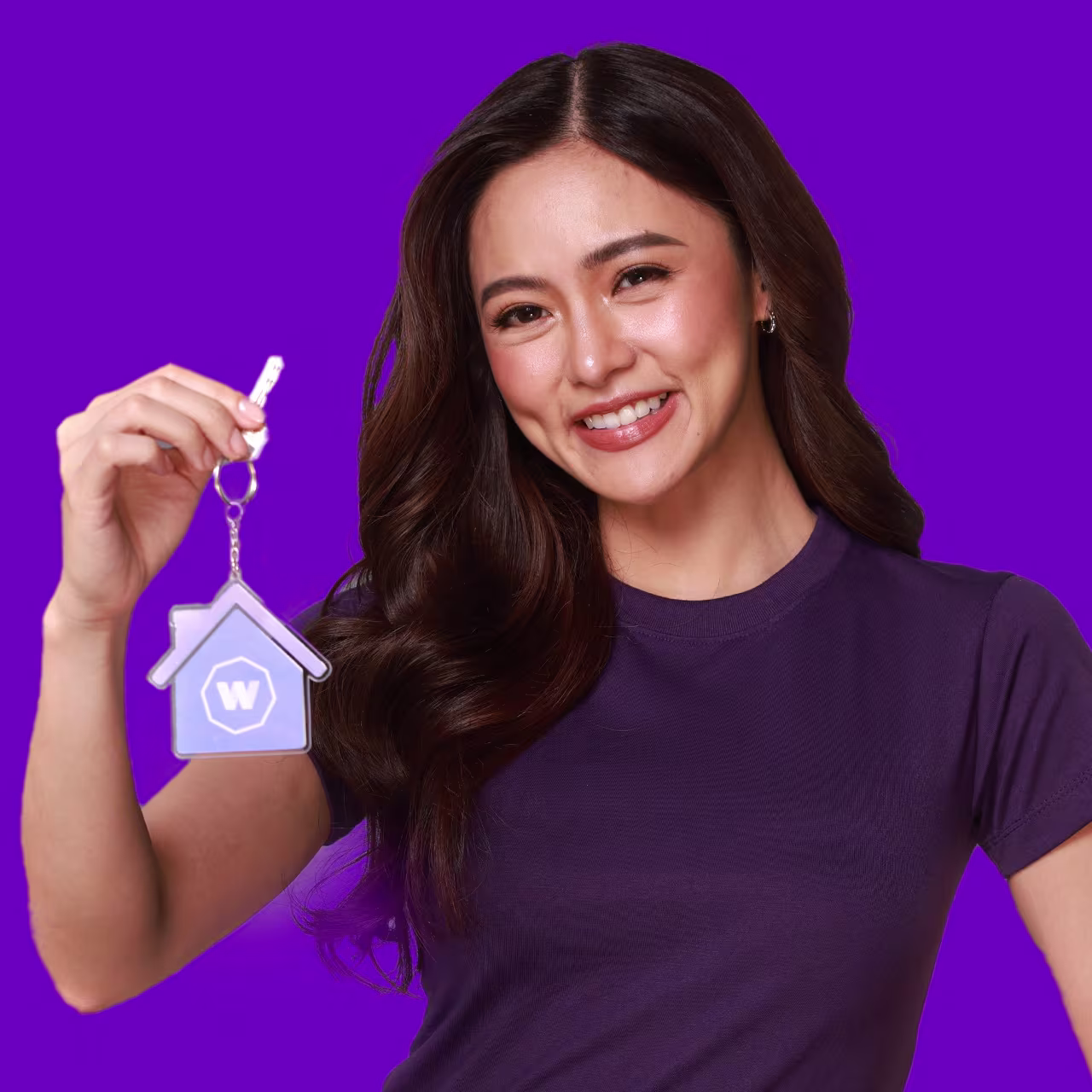 Win a Home - Philippines A Filipino woman holding a key attached to a keyring of a house with the WorldRemit logo on it