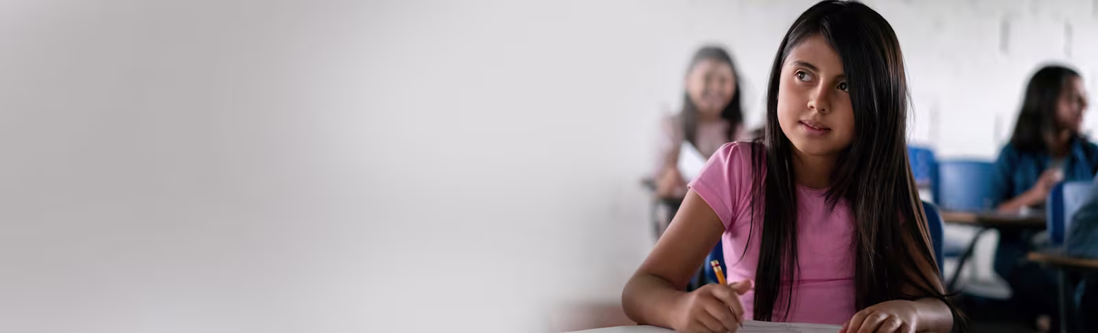 BTS Data Receive PR An image of a young girl in a classroom, smiling whilst writing