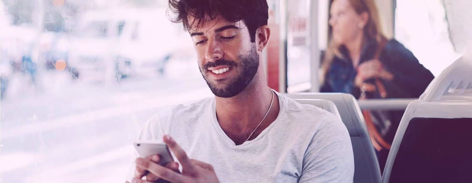 An image of a man on a bus using his phone