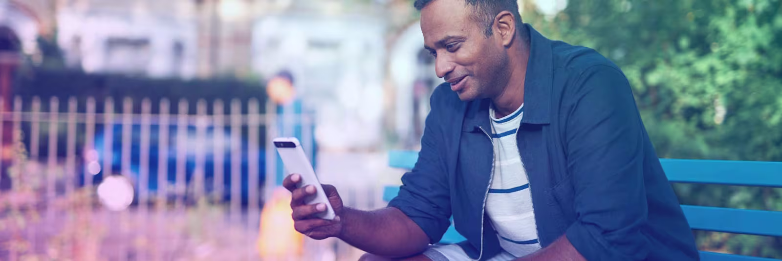 bank-transfer An image of a man sat on a bench and using his phone