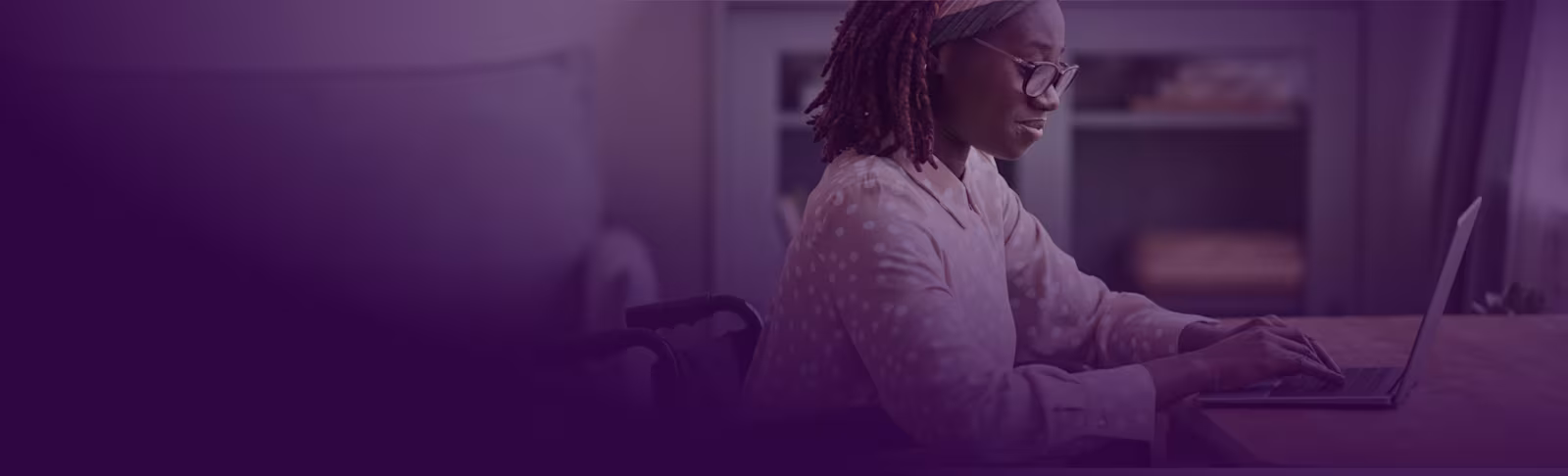 An image of a female student working on her laptop at her desk